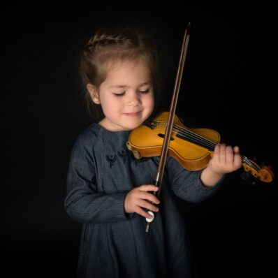 Kleines Mädchen mit Geige - Portrait auf schwarzem Hintergrund